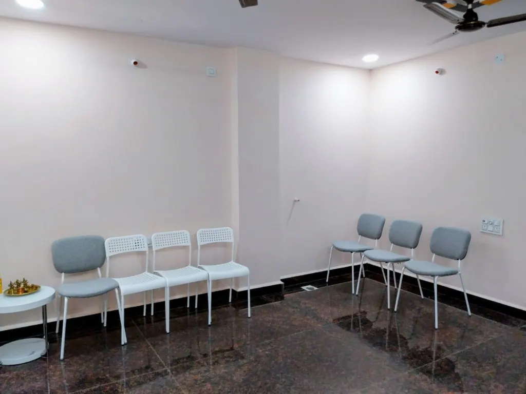 Bright waiting area at Cura Femina with rows of grey upholstered chairs, white chairs, a small side table, and polished dark flooring.